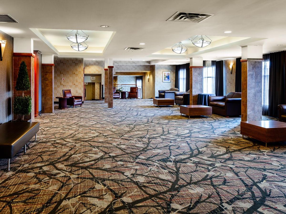 spacious, carpeted lobby area with tables and couches