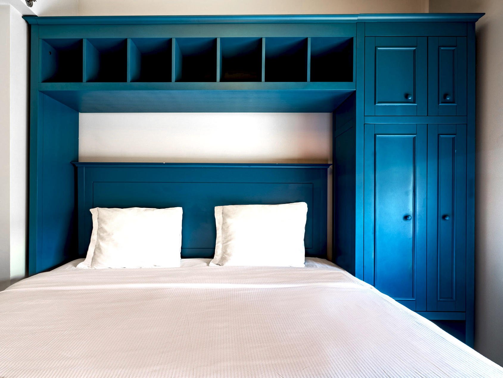 Queen bed with blue frame and cabinets