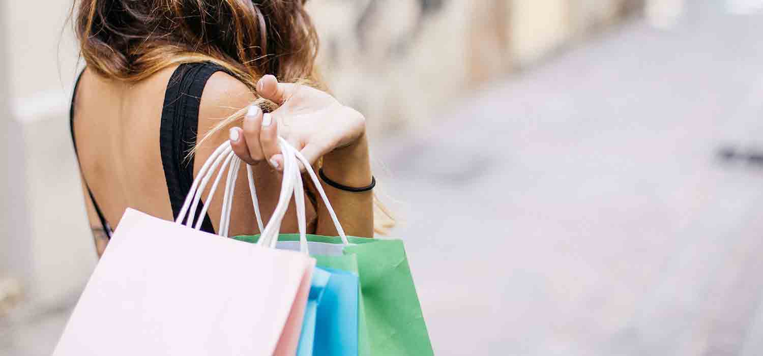 Woman holding colorful shopping bags over her shoulder.