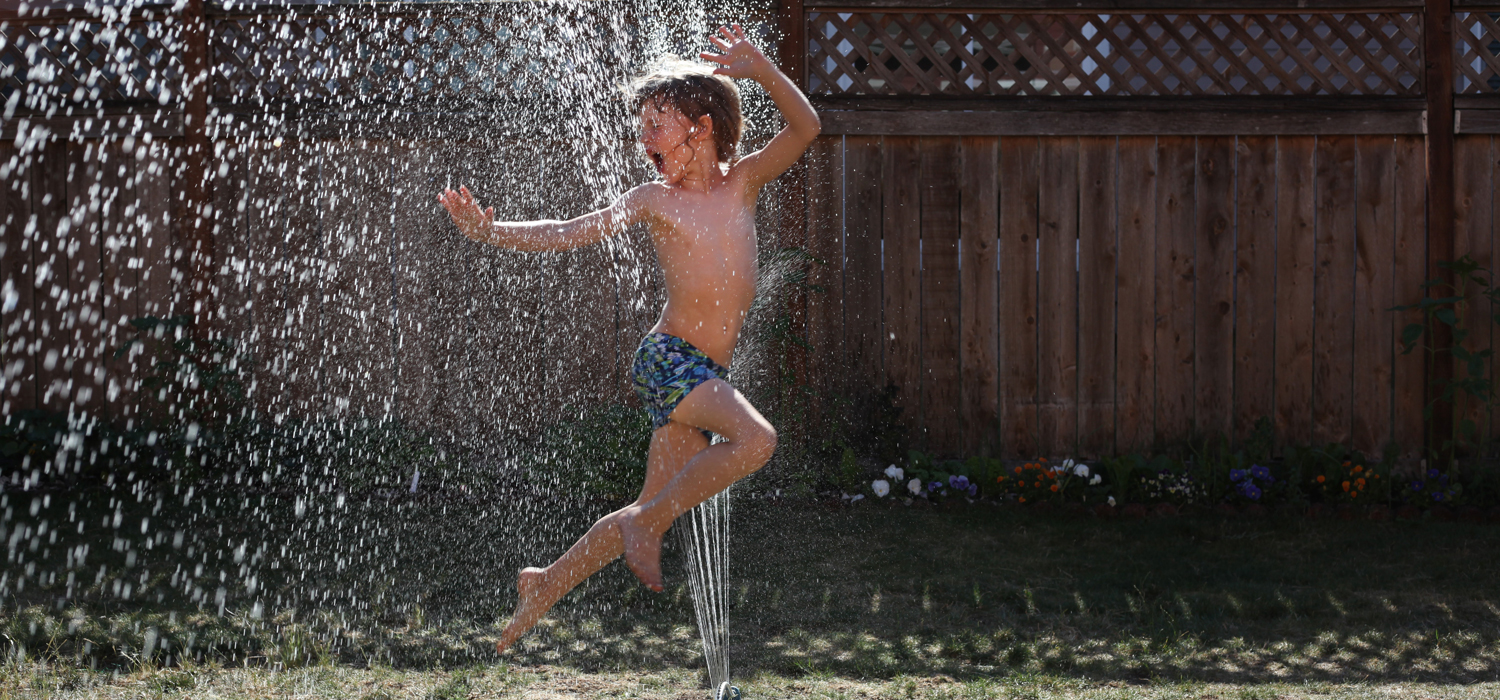 Boy jumping in sprinkler