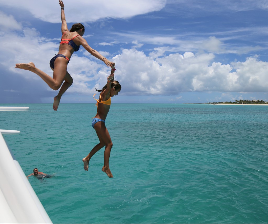 Two girls jumping into the sea near The Somerset On Grace Bay