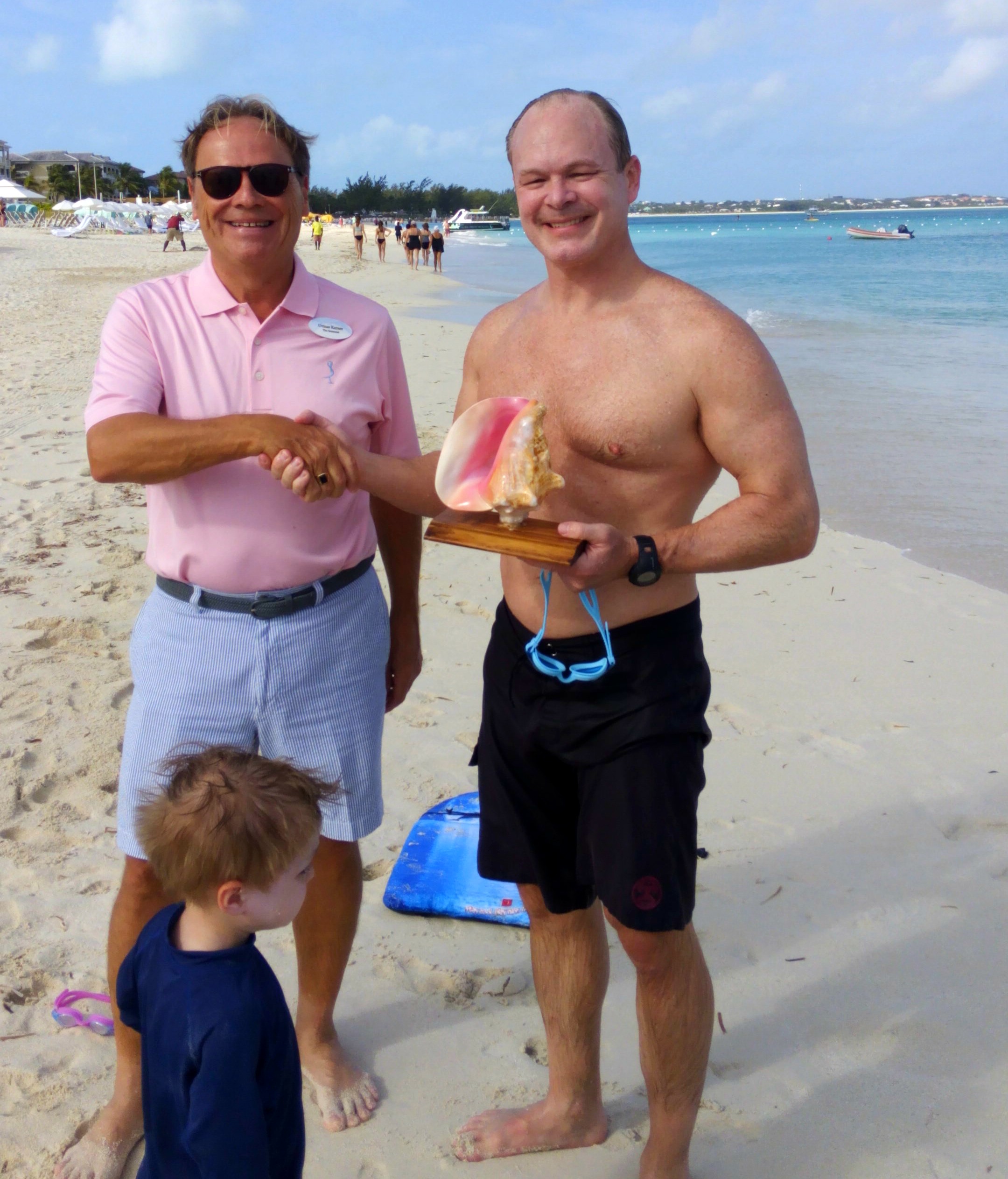 Two men handshaking by the beach, The Somerset On Grace Bay