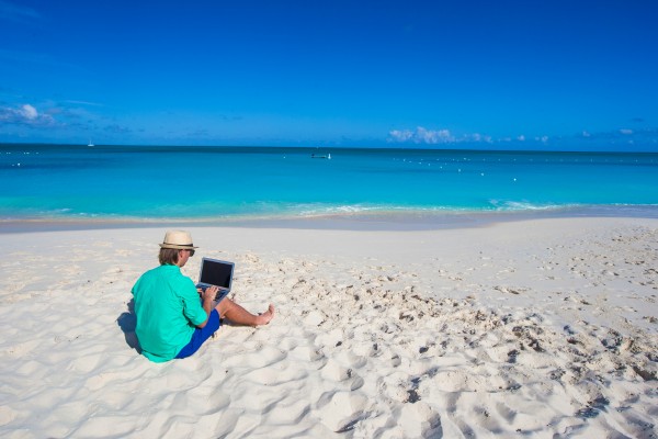 Man with a laptop at the beach near The Somerset on Grace Bay