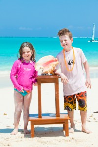 Two kids posing with a sea shell at Somerset on Grace Bay