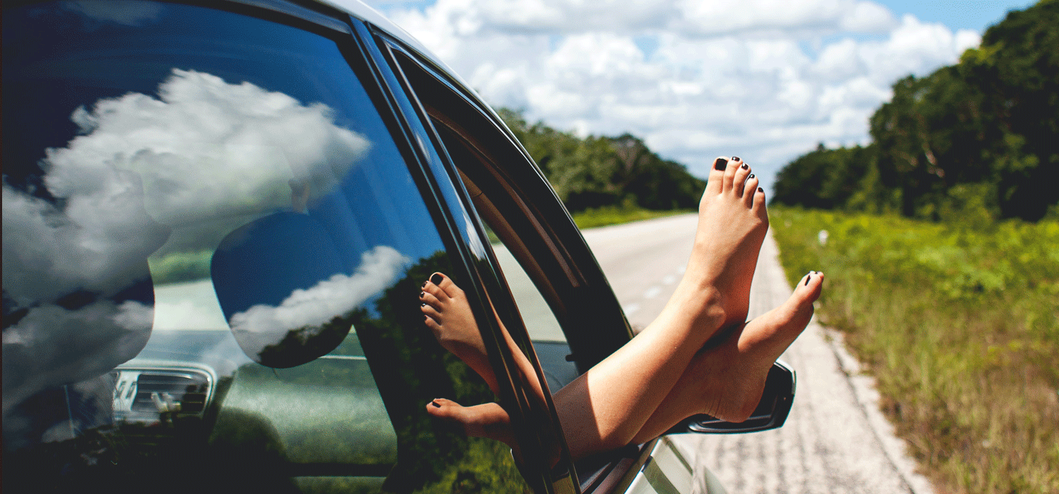 Feet out of car window on a road trip