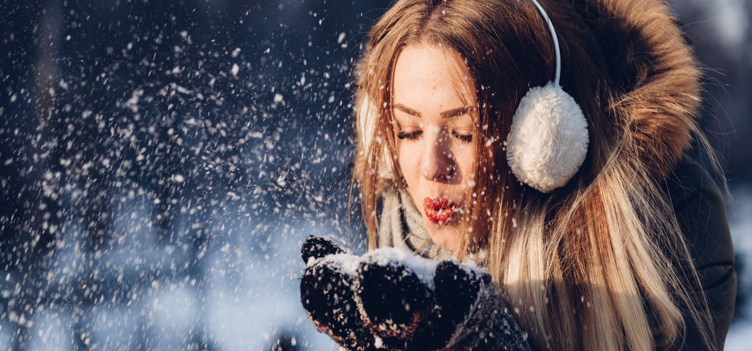 woman blowing snow from her hands